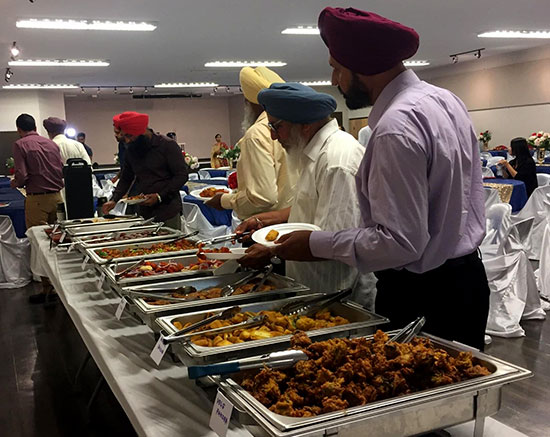 Gate of India Calgary catering event with guests serving Indian food at a buffet line